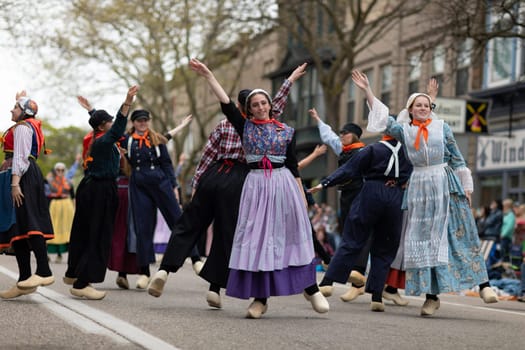Holland, Michigan, USA - May 11, 2019: Tulip Time Festival, Young women wearing traditional Dutch Clothing dancing in the streets of Holland, Michigan during the Festival