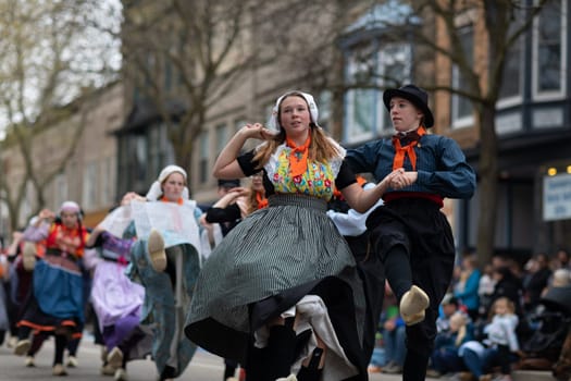 Holland, Michigan, USA - May 11, 2019: Tulip Time Festival, Young women wearing traditional Dutch Clothing dancing in the streets of Holland, Michigan during the Festival