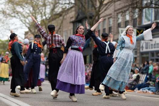 Holland, Michigan, USA - May 11, 2019: Tulip Time Festival, Young women wearing traditional Dutch Clothing dancing in the streets of Holland, Michigan during the Festival