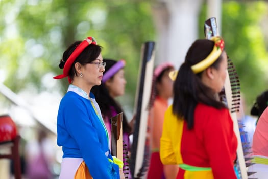Columbus, Ohio, USA - May 26, 2019: Columbus Asian Festival, Franklin Park, vietnamese woman wearing traditional clothing playing the Dan Tranh at the asian festival