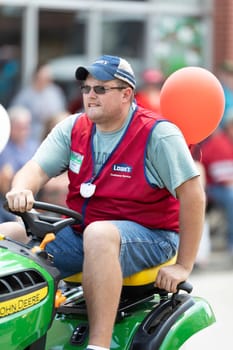 Buckhannon, West Virginia, USA - May 18, 2019: Strawberry Festival, Lowe's employee riding a John Deere Lawn mower, promoting Lowe's during the parade