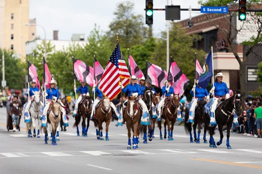 Louisville, Kentucky, USA - May 2, 2019: The Pegasus Parade, The Mid America Cowgirls riding horses and carrying flags during the parade