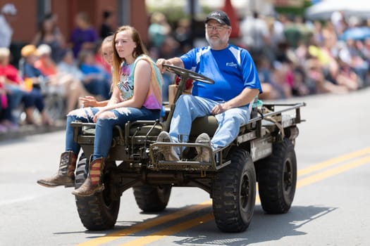 Buckhannon, West Virginia, USA - May 18, 2019: Strawberry Festival, Man driving a military M274 1/2 ton 4X4 mule, with two young women, during the parade