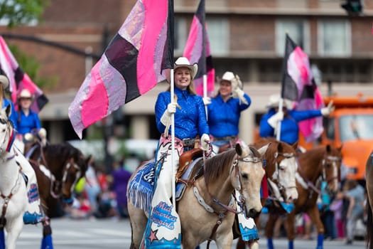 Louisville, Kentucky, USA - May 2, 2019: The Pegasus Parade, The Mid America Cowgirls riding horses and carrying flags during the parade