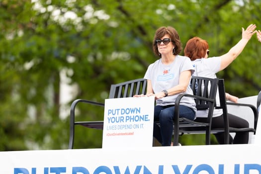 Louisville, Kentucky, USA - May 2, 2019: The Pegasus Parade, Woman holding a sign that says, put down your phone, lives depend on it, promoting driving safety