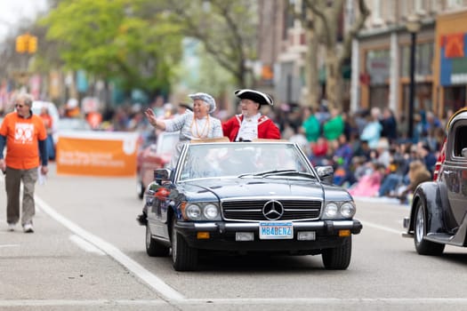 Holland, Michigan, USA - May 11, 2019: Tulip Time Parade, Man and woman wearing traditional dutch clothing riding on a Mercedez during the parade