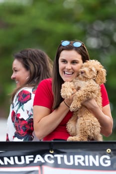Louisville, Kentucky, USA - May 2, 2019: The Pegasus Parade, young woman huging her pet dog, smiling, during the parade
