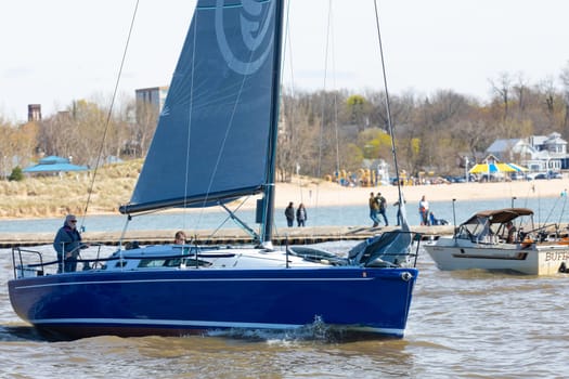 St. Joseph, Michigan, USA - May 4, 2019: Sail Boat leaving the harbor from St Joseph River and entering the Michigan Lake, passing by a fishing boat