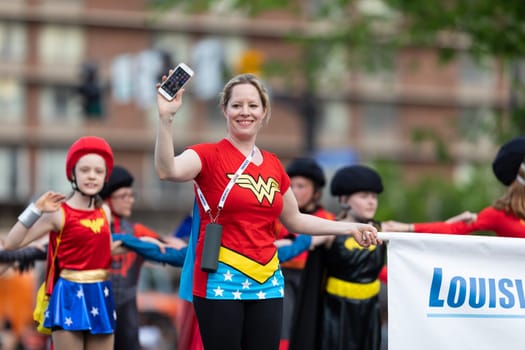 Louisville, Kentucky, USA - May 2, 2019: The Pegasus Parade, Members of Louisville Skating Academy dress up as wonder woman, skating down the street during the parade