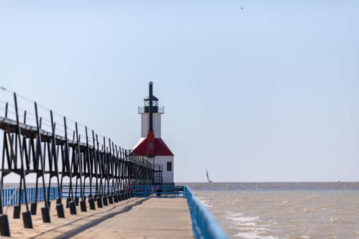 St. Joseph, Michigan, USA - May 4, 2019: View from the north pier, with the lighthouse and a sail boat leaving the harbor