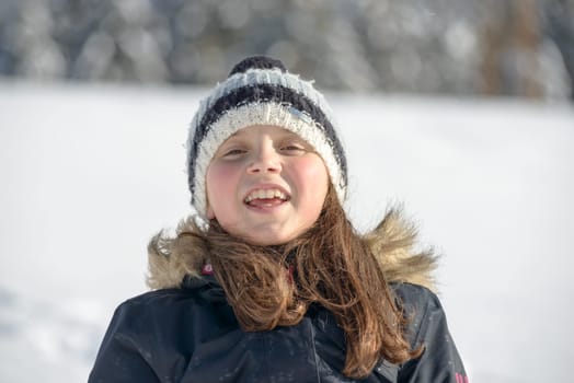 a smiling girl with a cap in the snow