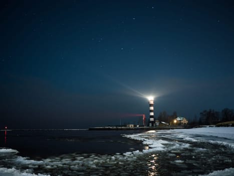 Riga Lighthouse in a starry night with frozen Baltic sea