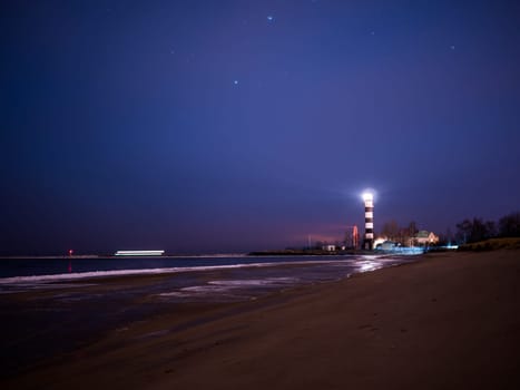 Black and white lighthouse at night in Baltic sea beach with stars