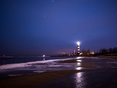Black and white lighthouse at night in Baltic sea beach with stars