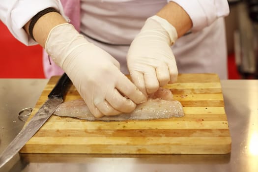 A chef is preparing and cutting a fresh fish