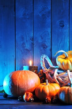 Halloween pumpkins in rattan basket in front of an old weathered wooden wall in blue light