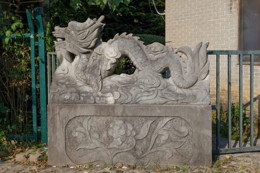 Figurine of a Chinese dragon made of concrete on a village street on a pedestal