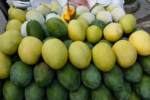 A bunch of green and yellow mangoes laid out in the market