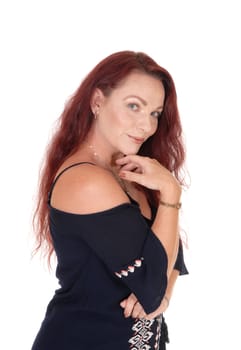 A waist up picture of a pretty woman with long red hair holding one.hand under her chin smiling into the camera, isolated for white.background.