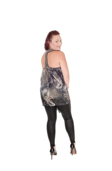 A gorgeous woman in black tights and a designer dress standing from.the back, looking over her shoulder, isolated for white background.