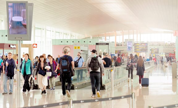 Barcelona, Spain, April 2019: people walking along the international departures corridor of El Prat airport in Barcelona, Spain