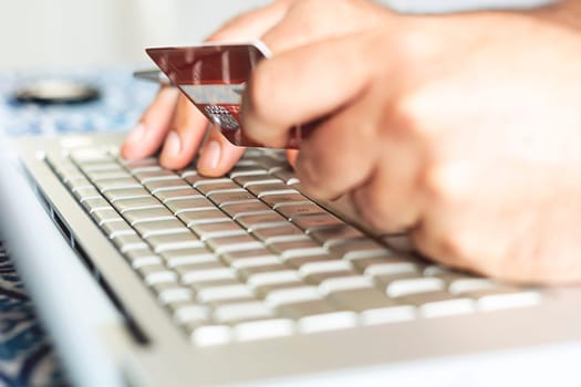 male person using a credit card for internet financial transactions. E-commerce and online shopping.