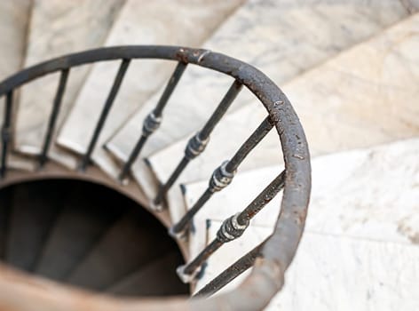ancient spiral staircase with marble steps and wrought iron handrail. Architecture and circular shape