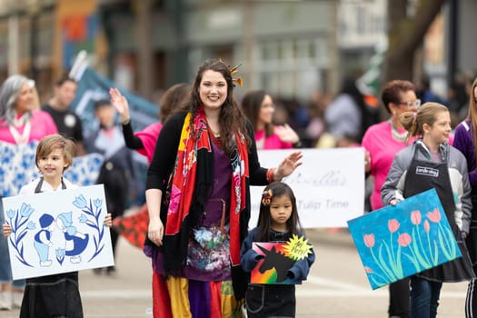 Holland, Michigan, USA - May 11, 2019: Tulip Time Parade, Woman accompanying children displaying their dutch related artworks during the parade