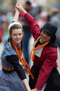 Holland, Michigan, USA - May 11, 2019: Tulip Time Festival, Young woman and man wearing traditional Dutch Clothing dancers in the streets of Holland, Michigan posing for a photo during the Festival