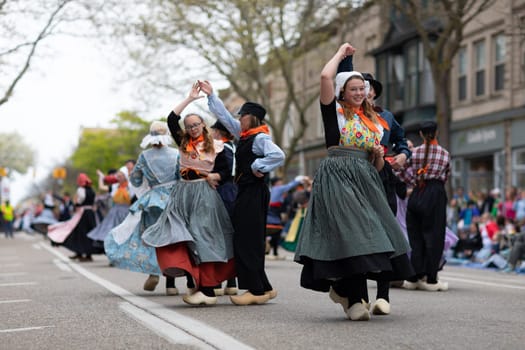 Holland, Michigan, USA - May 11, 2019: Tulip Time Festival, Young women wearing traditional Dutch Clothing dancing in the streets of Holland, Michigan during the Festival