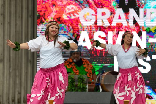 Grand Rapids, Michigan, USA - June 15, 2019: Asian Pacific Festival, Woman wearing traditional clothing performing a hula dance at the Rosa Parks Circle
