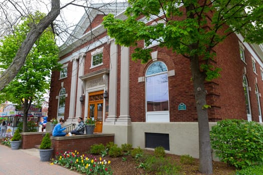 Holland, Michigan, USA - May 11, 2019: Couple eating lunch infront of the Woman's Literary Club building during the tulip time festival