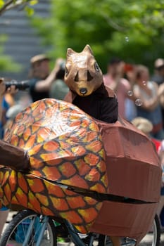 Cleveland, Ohio, USA - June 8, 2019: Parade the Circle, Person wearing a squirrel outfit riding a bicycle in shape of a nut