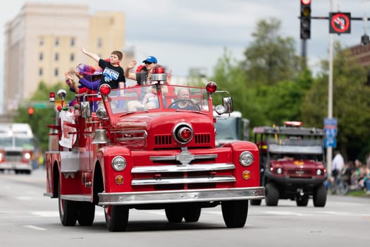 Louisville, Kentucky, USA - May 2, 2019: The Pegasus Parade, Man driving a antique firetruck during the parade, carrying children