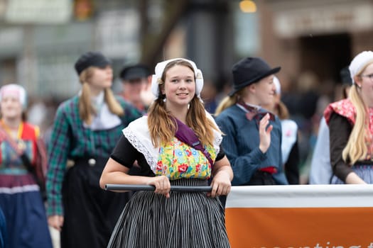 Holland, Michigan, USA - May 11, 2019: Tulip Time Parade, Young woman wearing traditional dutch clothing smiling, walking down the road during the parade