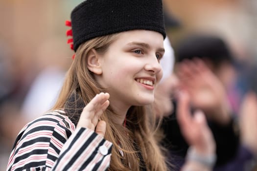 Holland, Michigan, USA - May 11, 2019: Tulip Time Parade, Young woman wearing traditional dutch clothing smiling, walking down the road during the parade