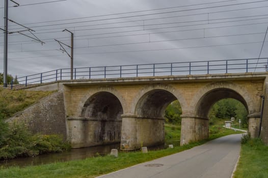 Railway bridge with three arches, two for the river of the tone and one for the tarmaker road in the city of Virton in the province of Luxembourg in Belgium