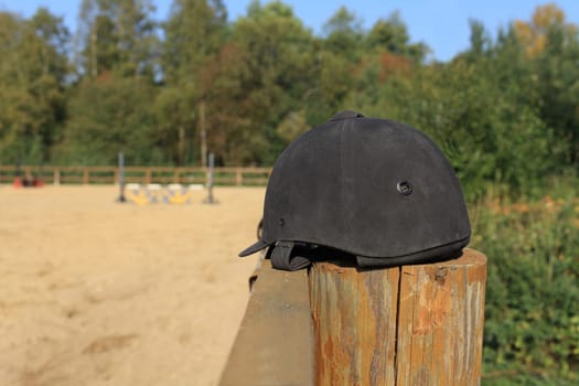 black suede jockey helmet in the foreground on the fence still life