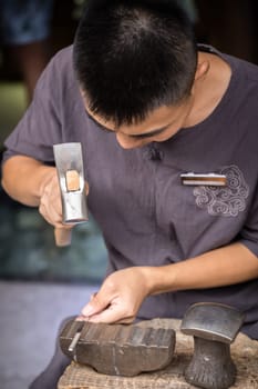 Xian, China -  July 2019 : Man using hammer to make crafts on the street market in the Muslim Quarter, Xian town, Shaanxi Province