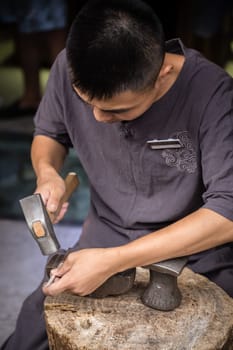 Xian, China -  July 2019 : Man using hammer to make crafts on the street market in the Muslim Quarter, Xian town, Shaanxi Province