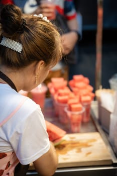 Xian, China -  July 2019 : Woman cutting watermelon into small pieces to be sold in plastic cups or blended for juice in a stall in Muslim Quarter