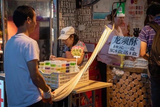 Xian, China -  July 2019 : Older man preparing dough for noodles and pasta in a traditional way on the street in the Muslim Quarter
