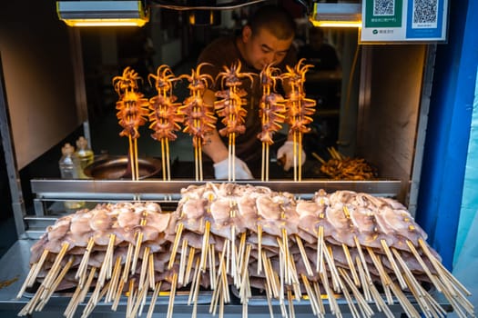 Xian, China -  July 2019 : Meat, snacks, calamari and fried baby octopus vendor selling food on the street in the Muslim Quarter