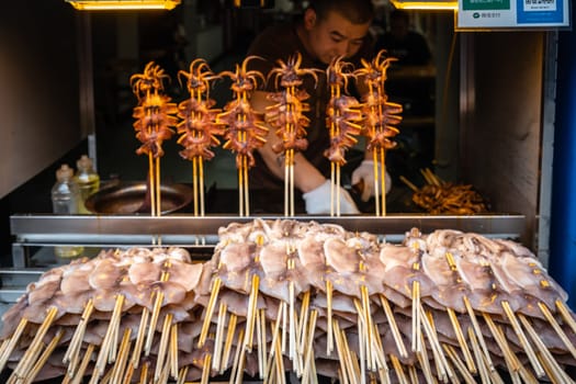 Xian, China -  July 2019 : Meat, snacks, calamari and fried baby octopus vendor selling food on the street in the Muslim Quarter