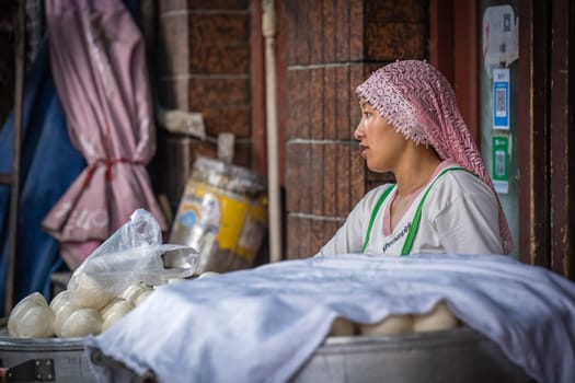Xian, China -  July 2019 : Muslim woman selling baozi buns and dough on the food street in the Muslim Quarter
