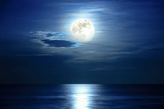 Super full moon and cloud in the blue sky above the ocean horizon at midnight, moonlight reflect the water surface and wave, Beautiful nature landscape view at night scene of the sea for background