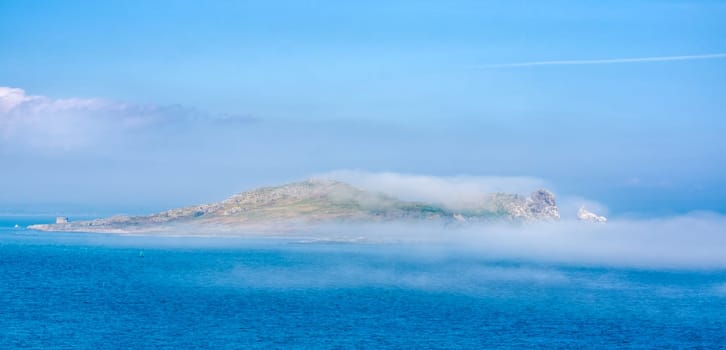 Low lying fog or mist approaching and covering Irelands Eye island, unusual phenomenon, panoramic view from Howth, Dublin, Ireland