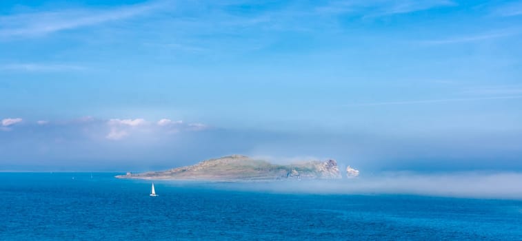 Low lying fog or mist approaching and covering Irelands Eye island, unusual phenomenon, panoramic view from Howth, Dublin, Ireland