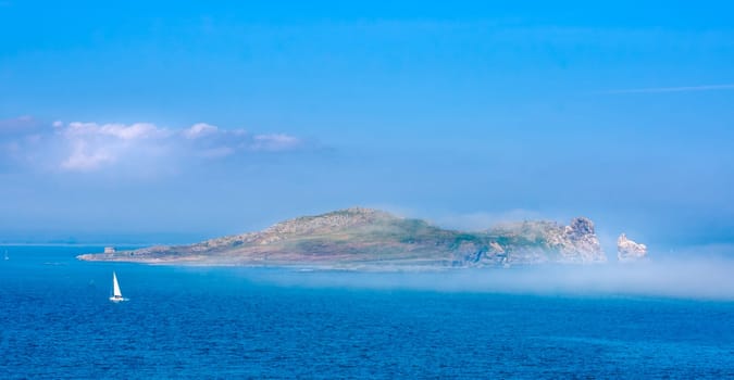 Low lying fog or mist approaching and covering Irelands Eye island, unusual phenomenon, panoramic view from Howth, Dublin, Ireland