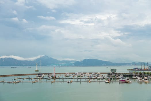 View of the bay with fishing boats and mountains away in cloudy weather, Shenzhen, China, Asia